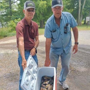 two men show off a whole cooler of fish