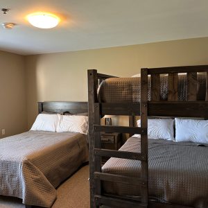 A full size bed next to a bunk bed