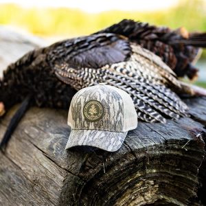 Old Cypress Lodge hat and turkey laying on a log